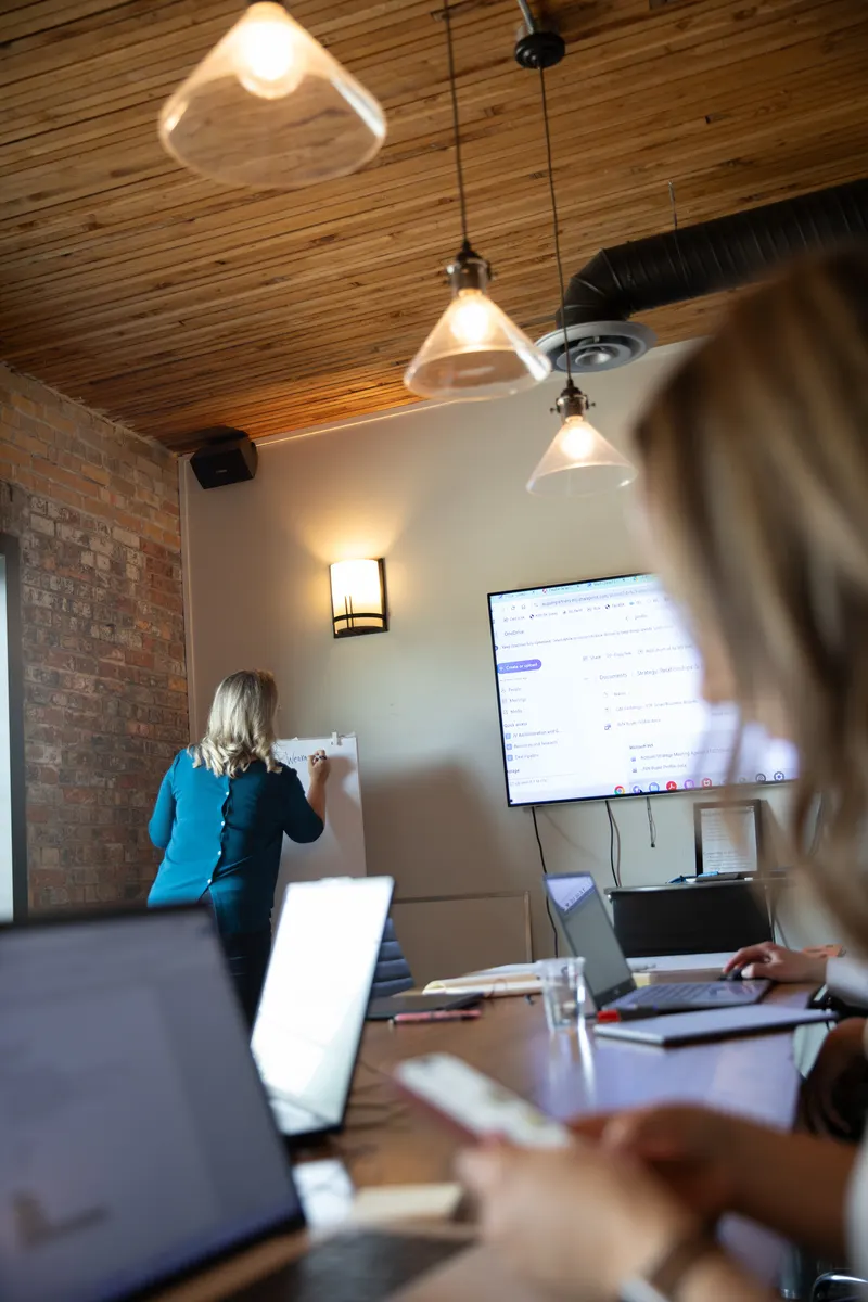 Leslie Doka leading a whiteboard session with the Acquen team in the boardroom